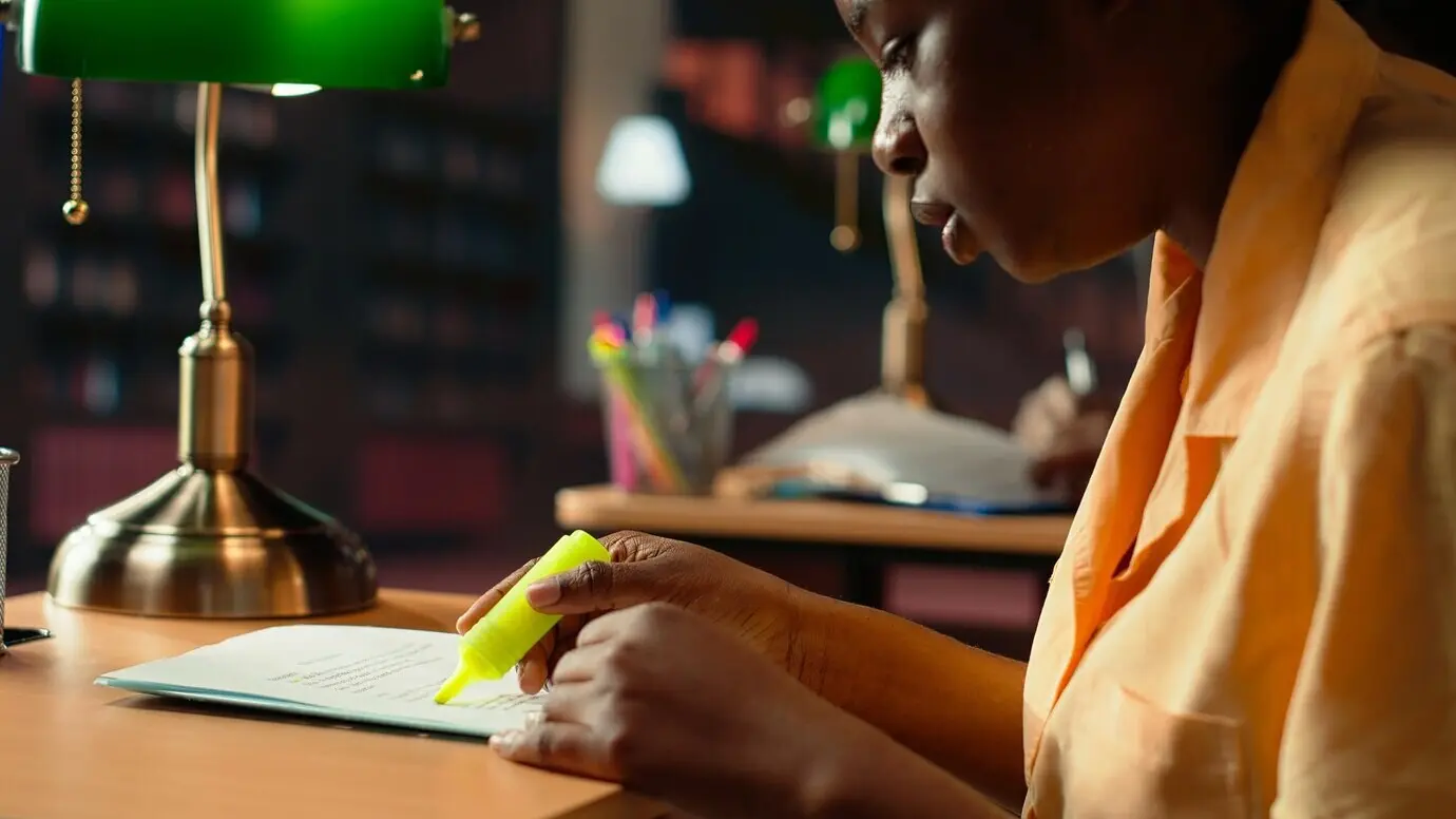 Студент колледжа подчеркивает важные фразы в записях с занятий.